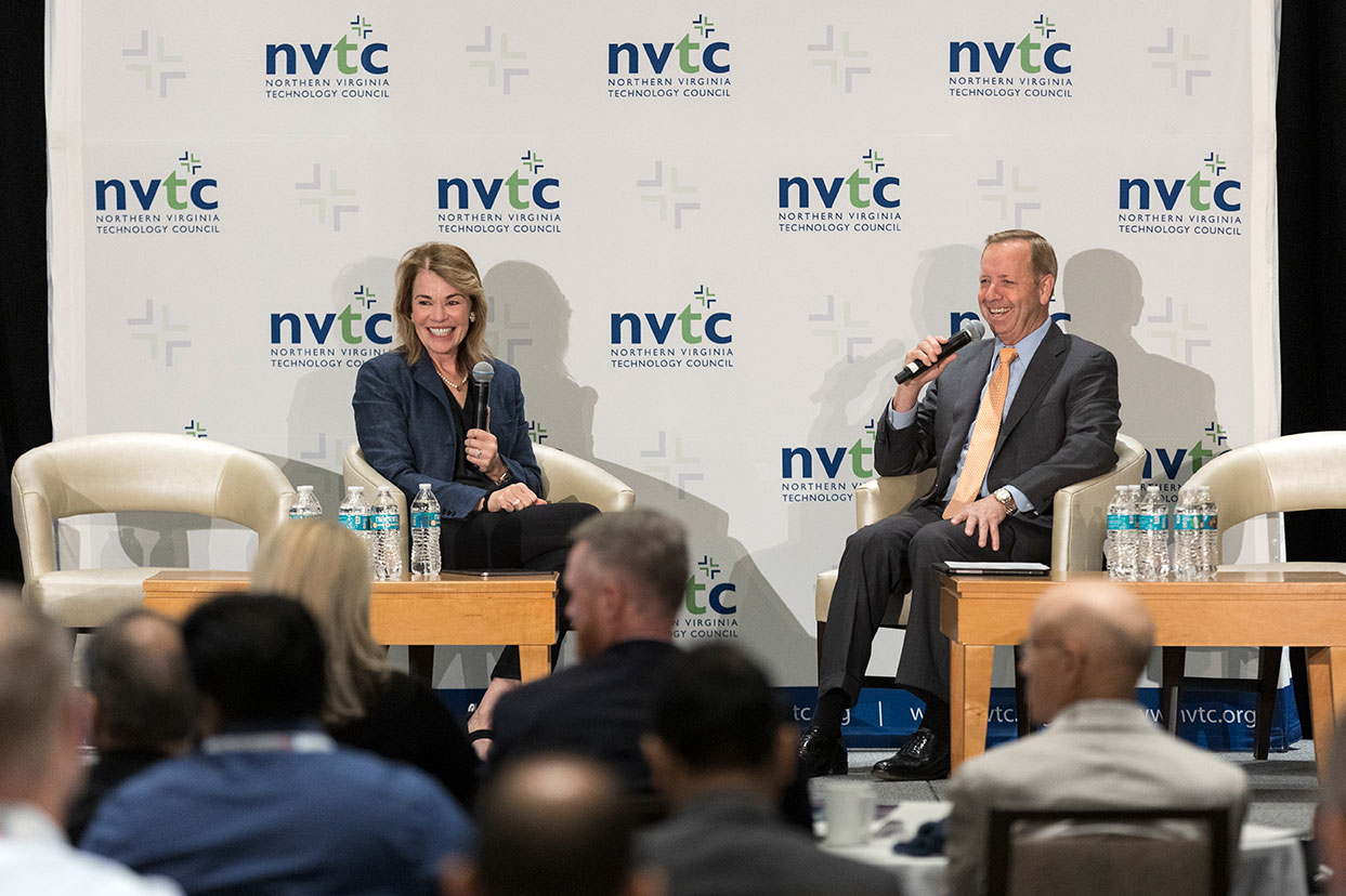 A man and a woman speaking as part of a panel at an NVTC event in front of an audience