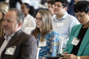 Young woman among other people in the audience at Aim High Kickoff event