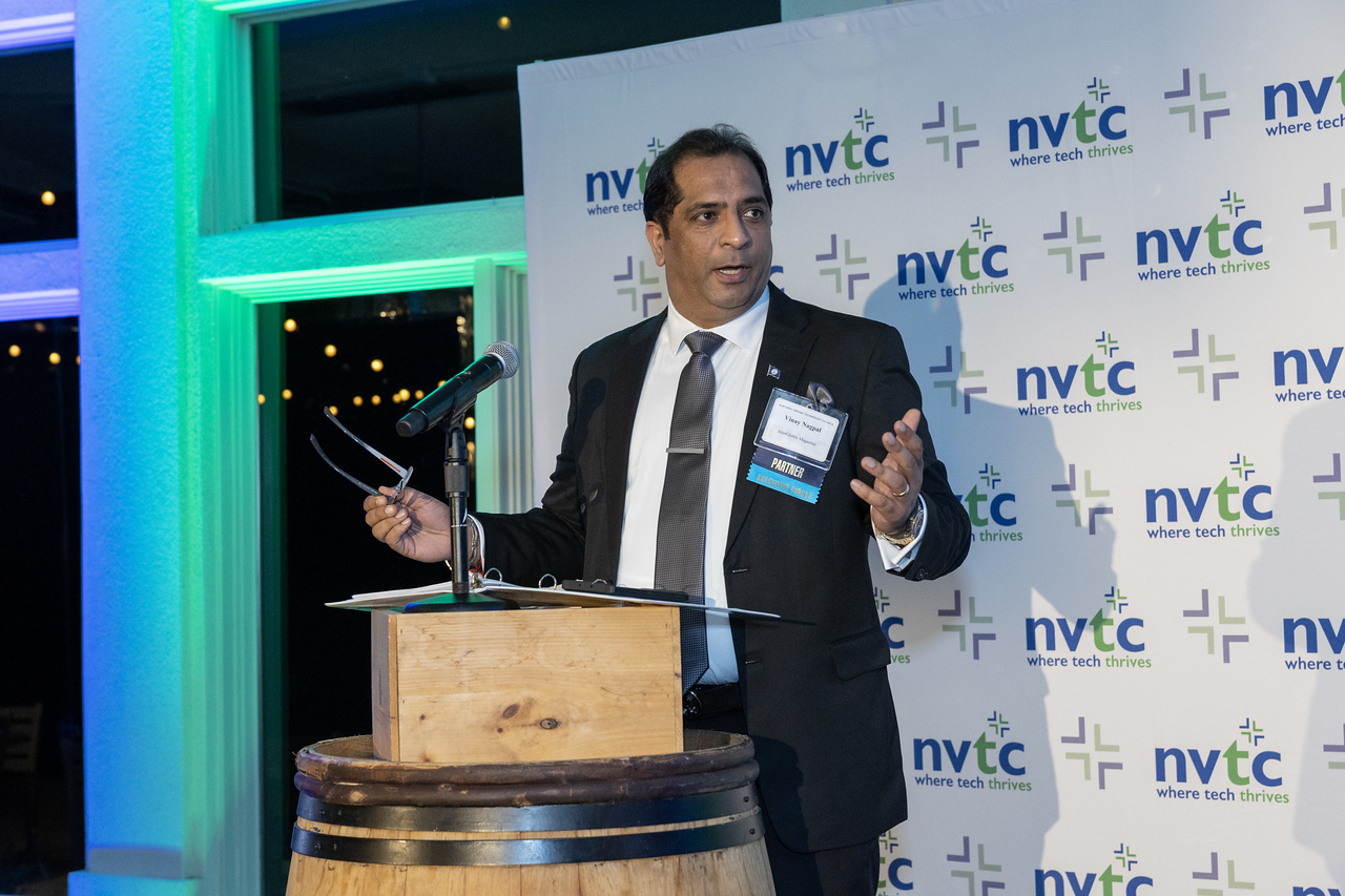 Vinay from Interglobix in front of an NVTC step-and-repeat presenting at a podium