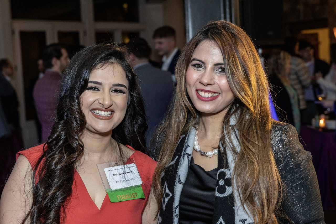 Two women, one in a red dress and the other in a black one with a blazer on at the NVTC Data Center Awards