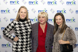 Photo of three women in front of a step and repeat with NVTC's logo on it